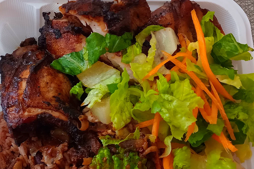 Jerk chicken with rice and peas and a fresh salad of lettuce and shredded carrot